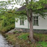 a small white house sitting next to a river