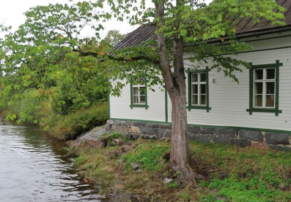 a small white house sitting next to a river