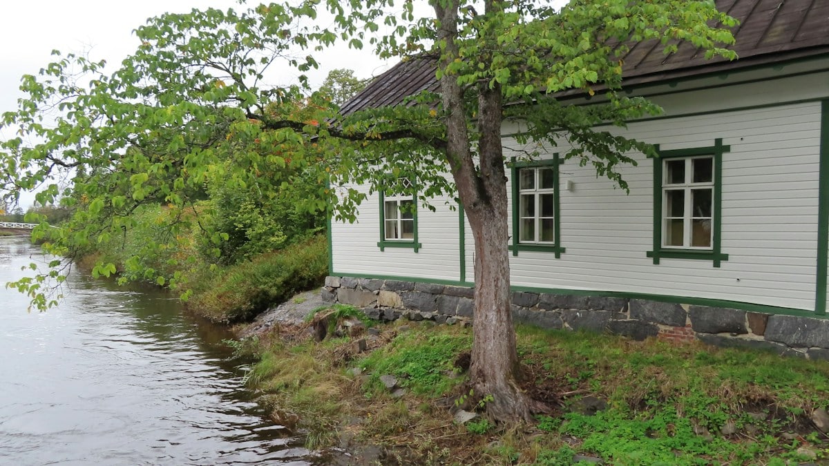 a small white house sitting next to a river